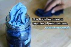 a jar filled with blue cleaning wipes on top of a wooden table next to a person's hand