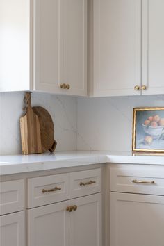 a kitchen with white cabinets and marble counter tops, including a cutting board on top of the cabinet doors