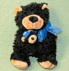 a black teddy bear with a blue ribbon around its neck