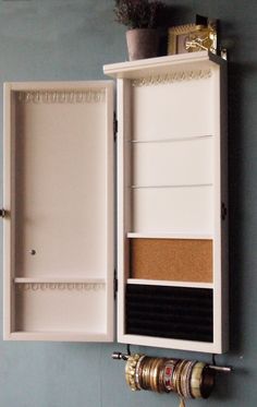 an open medicine cabinet on the wall with several bottles and other items in it next to a plant