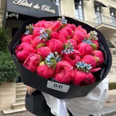 a person holding a bouquet of flowers in front of a building