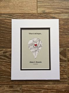 a white frame with a red heart in it on top of a wooden floor next to a wall