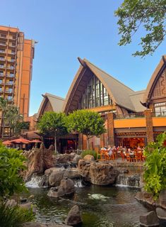 a large building sitting next to a river in a lush green forest filled with trees