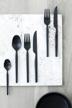 five forks, two spoons and one knife on a white surface with some dirt