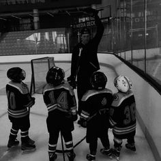 an ice hockey coach is giving instructions to his young players on the rink at night