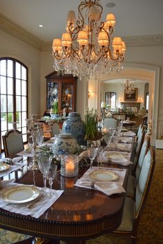 the dining room table is set with place settings for six people and there are chandeliers hanging from the ceiling