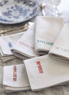 napkins with french words on them are sitting on a marble countertop next to silverware