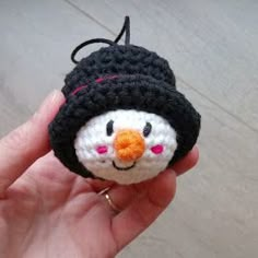 a hand holding a small crocheted penguin ornament