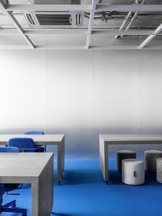 an empty office with blue chairs and white tables in the center, on a bright blue carpeted floor