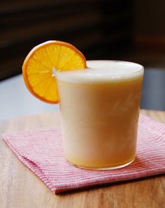 an orange slice sitting on top of a table next to a glass filled with milk