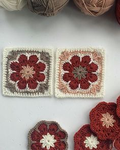 two crocheted coasters with red and white flowers on them next to balls of yarn