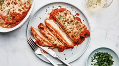 two plates with meat covered in sauce and garnished with parmesan cheese