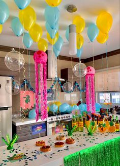 balloons and streamers are hanging from the ceiling above a table with desserts on it