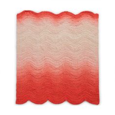 an orange and white knitted blanket with wavy lines on the bottom, in shades of red