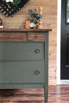 an old dresser is painted green and has some flowers on the top, along with other items