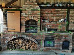 a brick oven with lots of wood stacked on it's sides and shelves filled with bottles