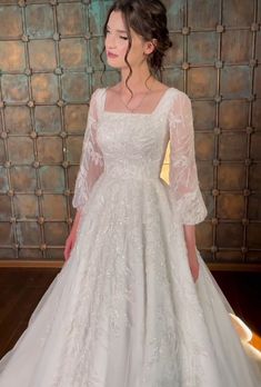 a woman in a white wedding dress standing next to a wall with lights on it