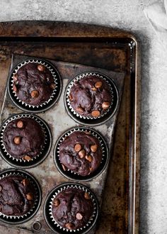 chocolate cupcakes in a muffin tin on a baking sheet, ready to be eaten