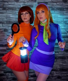 two women dressed up in costumes and holding magnifying glass with light shining on them