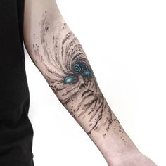 a man with a tattoo on his arm has a blue eyeball in the center