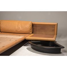 a bed with a brown leather headboard and footstool next to a table