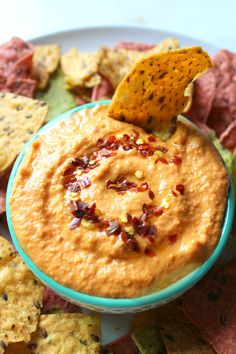 a blue bowl filled with dip surrounded by tortilla chips