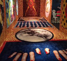 an art exhibit with multiple paintings on the floor and one woman's feet in the middle