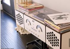 there is a table with magazines on it and a radio in front of the bookshelf