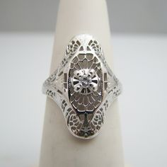 "For sale: (1) g004 Antique 10kt White Gold Diamond Statement Ring PLEASE READ ENTIRE DESCRIPTION BEFORE PURCHASING Pre-owned item. Good condition. Please see pictures for details. Sold as is, as seen on pictures. This ring contains one center diamond (round cut). It is stamped. Specifics: 10k White gold Diamonds: 0.05CT/TCW Size: 4.5 (U.S.) Width: 20.6 mm Total Weight: 1.9 grams Please be 100% sure of your purchase before buying, as we do not offer refunds. We are more than happy to provide any Elegant White Gold Engraved Ring Stamped 14k, Formal Silver Rings In 14k Gold, Antique Silver-colored 14k Gold Diamond Ring, Antique Silver 14k Gold Diamond Ring, Antique Silver Diamond Ring In 14k Gold, Antique 14k White Gold Jewelry With Diamond Accents, Formal Engraved 14k White Gold Jewelry, Formal 14k White Gold Engraved Jewelry, Engraved 14k White Gold Jewelry For Formal Occasions