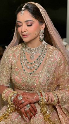 a woman in a bridal gown with jewelry on her face and hands clasped together