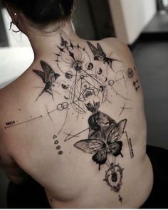 a woman's back tattoo with butterflies and circles on her left shoulder, in black ink