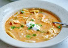 a white bowl filled with soup and some sour cream on top of the soup is garnished with parsley