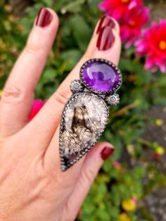 A beautiful, bold talon ring, completely handmade from recycled sterling silver. It holds a deep purple amethyst that seems to glow in the light, and a delicately patterned plume agate stone, with a subtle shimmer and hint of purple. A gorgeous match of stones, this ring is a real statement piece! It sits on a wide, adjustable ring band. All metal is eco solid sterling silver and fine silver and it has been oxidised for a dark, and slightly gothic finish. Mystical Sterling Silver Jewelry With Large Stone, Purple Gemstone Fusion Rings, Unique Purple Cabochon Jewelry, Mystical Amethyst Ring In Sterling Silver, Unique Amethyst Open Ring, Mystical Sterling Silver Amethyst Ring, One Of A Kind Amethyst Jewelry, Unique Cabochon Gemstones, Unique One-of-a-kind Amethyst Jewelry