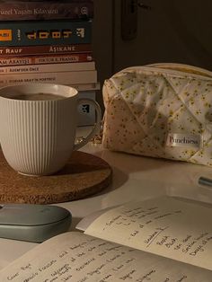 a cup of coffee sitting on top of a desk next to books and a mouse