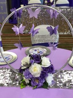 purple and white flowers are sitting on a table with silver sequins around it