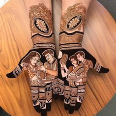 two hands with henna designs on them sitting on top of a wooden table next to each other