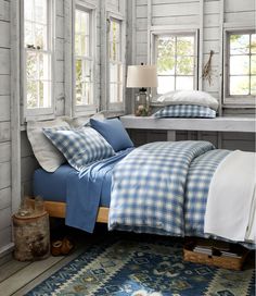 a bed with blue and white checkered comforter in a room next to two windows