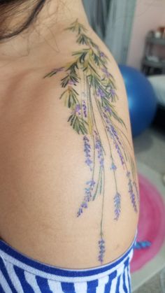 the back of a woman's shoulder with lavender flowers on her left arm and chest