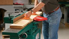 a man standing in front of a table sawing with an orange object on it