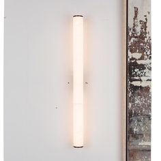 a white wall light mounted on the side of a wall next to a brick wall