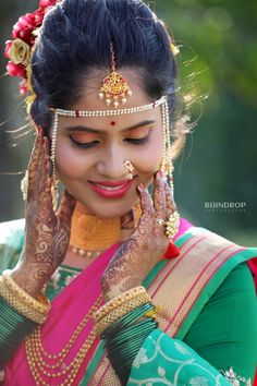 a woman with henna on her face and hands in front of her face, looking down