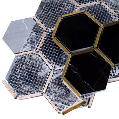 the black and gold hexagonal tiles are arranged on top of each other