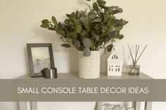 a small console table decorated with plants and other decorating items on top of it