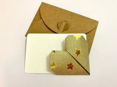 an envelope with gold stars on it next to a paper origami heart and star brooch