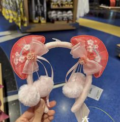 a person holding up two ears with flowers on them in front of a store display