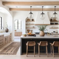 a kitchen with an island and two chairs in front of the counter top, surrounded by open shelves