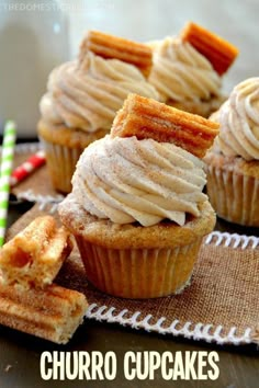 some cupcakes with icing and cinnamon sticks on a cloth next to them