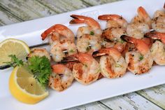 shrimp is served on a white plate with lemon wedges