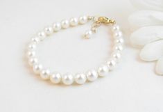 "A classic real freshwater pearl bracelet for newborn, infant, baby, child, little girl, tween or teen. This keepsake bracelet is created with Grade-A 5.5mm round freshwater pearls and a 14K gold-filled oval lobster clasp with a 1/2\" \"Grow with Me\" extender chain. Arrives packaged in my signature high-quality reusable canvas gift bag. Beautiful and ready for gift giving. S I Z I N G . G U I D E The bracelet should be 3/4\" larger than her snug wrist measurement. If you are unable to measure, Elegant Adjustable Pearl Bracelet For Baptism, Elegant Pearl Jewelry For Baptism, Elegant Pearl White Jewelry For Baptism, Classic White Bracelets For Mother's Day, Elegant Pearl White Jewelry For First Communion, Elegant Round Jewelry For Baptism, Classic Adjustable Jewelry For First Communion, Classic White Pearl Bracelet For Mother's Day, Elegant Pearl Bracelet For First Communion