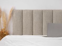 an open laptop computer sitting on top of a bed next to tall dry grass and plants